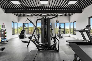 A modern gym with various exercise equipment, large windows, and a view of the outdoors. - Private Pool | 2BR Retreat | Near Eagle Beach (Noord)