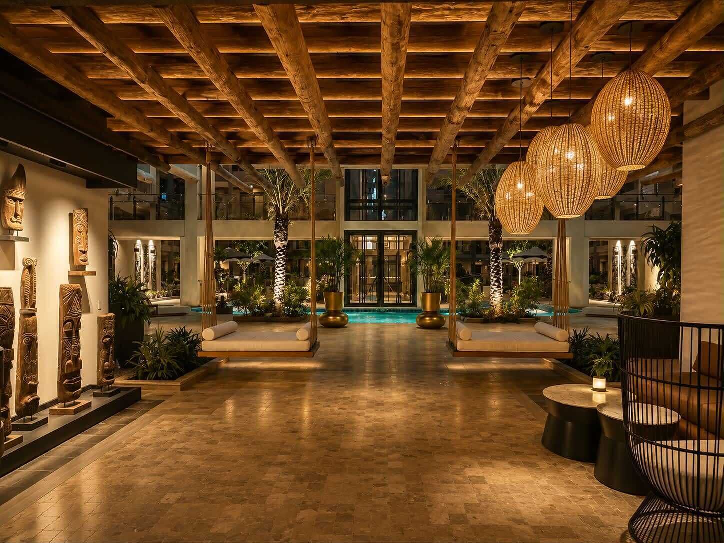 A spacious indoor area with a pool, wooden ceiling beams, and seating areas.