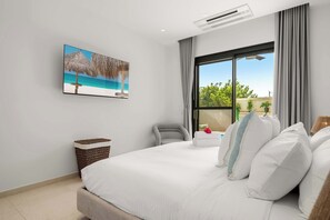 Ein Hotelzimmer mit einem großen Bett, einem Wandfernseher und einem Fenster mit Vorhängen.