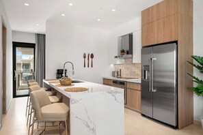 A modern kitchen with a marble island, stainless steel appliances, and a view to the outside. - Breezy Balcony | Top-Floor 1BR | Near Eagle Beach (Noord)