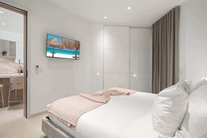 Ein modernes Schlafzimmer mit einem Bett, einem an der Wand befestigten Fernseher und einem Badezimmer mit Dusche.
