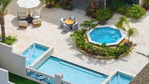 A rooftop pool area with a hot tub, lounge chairs, and a thatched-roof structure. - Breezy Balcony | Top-Floor 1BR | Near Eagle Beach (Noord)