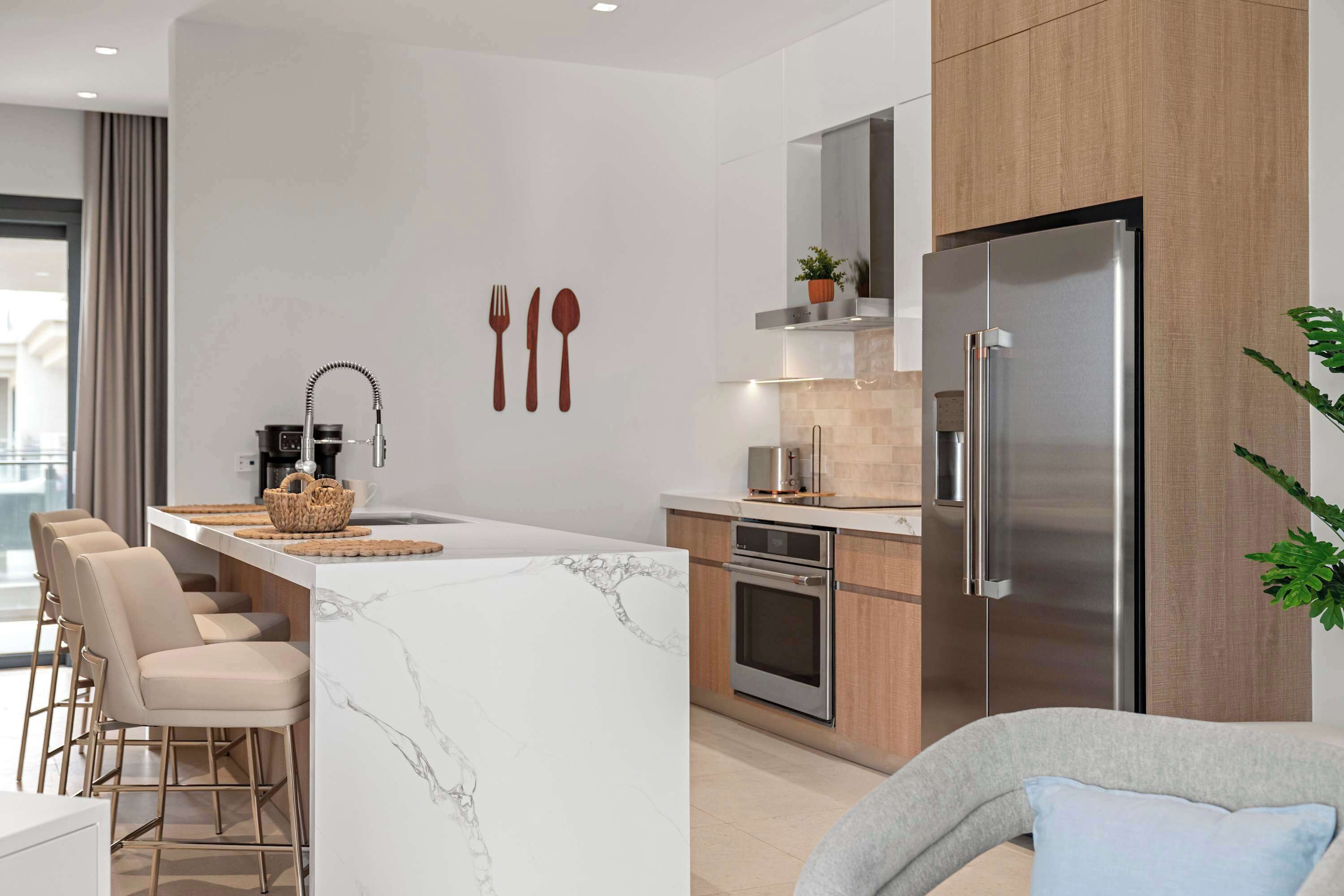A modern kitchen with a central island, stainless steel appliances, and a seating area with chairs.