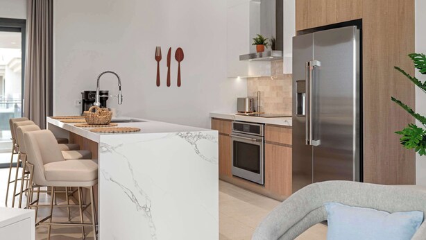 A modern kitchen with a central island, stainless steel appliances, and a seating area with chairs. - Breezy Balcony | Top-Floor 1BR | Near Eagle Beach (Noord)