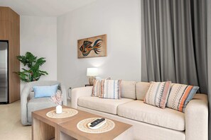 Ein modernes Wohnzimmer mit Sofa, Sessel, Tisch, Pflanze, Gemälde und Lampe.