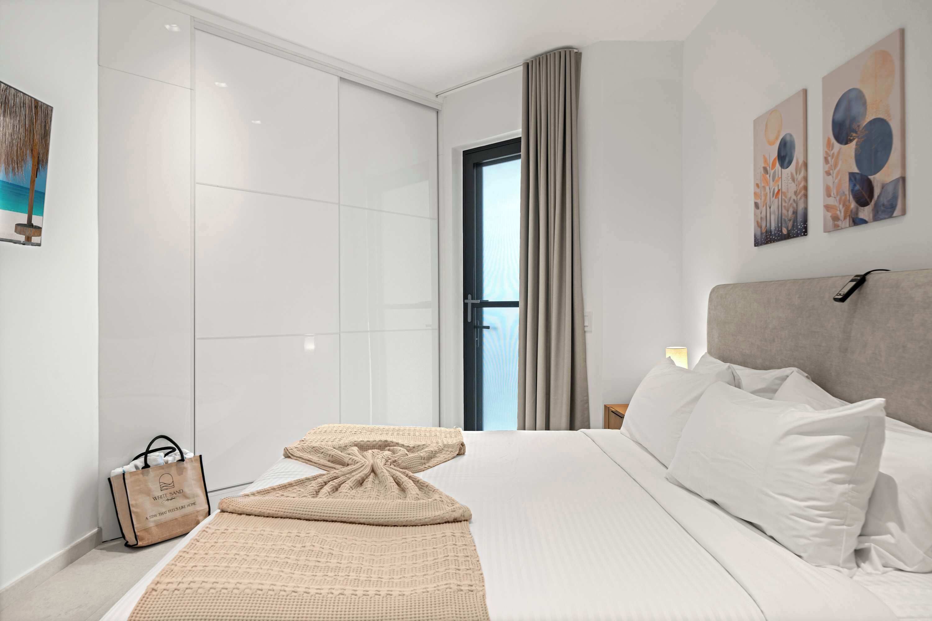 Habitación de hotel moderna con una cama grande, vistas al exterior a través de una ventana y obras de arte en las paredes.
