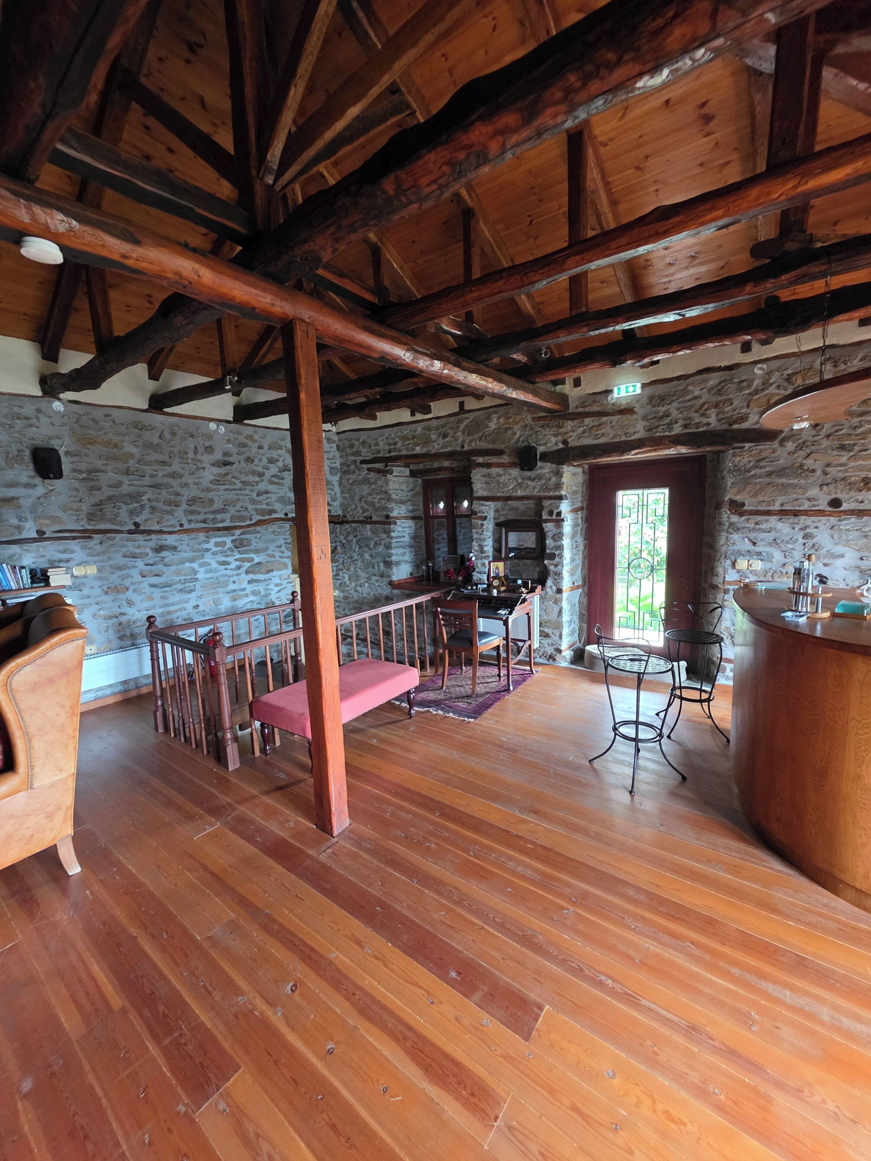 A rustic interior with a wooden dining table, a bar area, and stone walls.