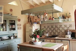 A kitchen with hanging utensils, a stove, and a dining area with a table and chairs.