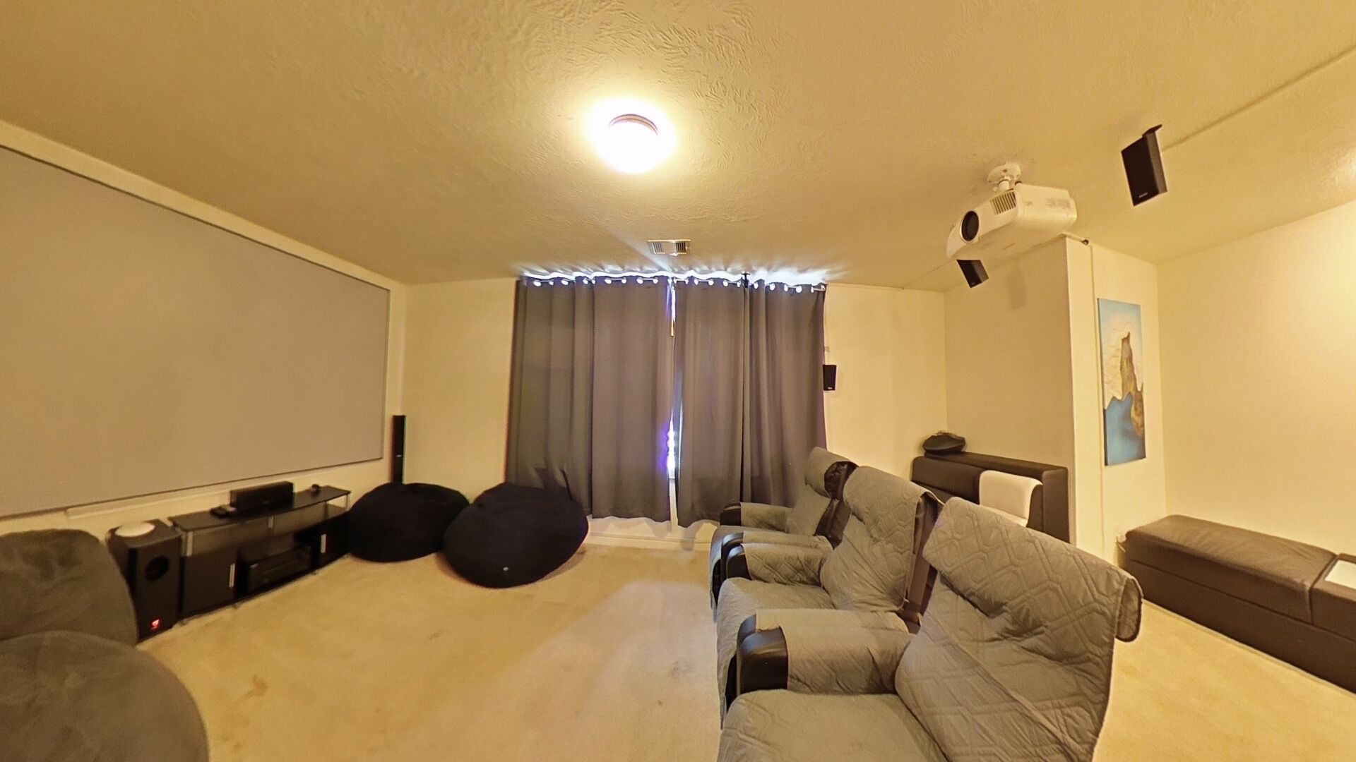 Ein Zimmer mit einem großen Bett, einem Flachbildfernseher, einem Deckenprojektor und einer Wandprojektion.