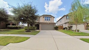 A residential street with two houses, a driveway, and a tree. - 3 Bedrooms w/4 Beds | Home Theater | Massage Bed (Houston)