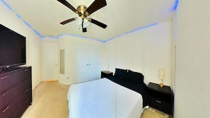 A bedroom with a bed, a ceiling fan, a wardrobe, a bedside table, and a TV. - 3 Bedrooms w/4 Beds | Home Theater | Massage Bed (Houston)