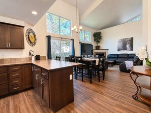 A spacious living area with a dining table, a fireplace, and a large window providing natural light. - Unwind at Midtown Haven (Coeur d'Alene)