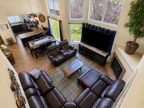 A spacious living area with a large leather sofa, a flat-screen TV, and a dining area with a kitchen in the background. - Unwind at Midtown Haven (Coeur d'Alene)
