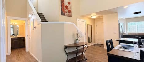 Une cuisine spacieuse avec un coin repas, un plancher en bois et un escalier menant à un autre niveau.