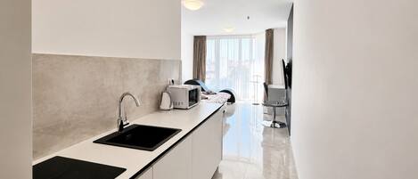 A modern kitchen with a black countertop, white cabinets, and a built-in microwave.
