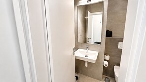 Un baño moderno con un lavabo blanco, un espejo y un inodoro.