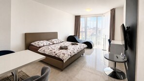 Una habitación de hotel moderna con cama, escritorio, silla y televisor.