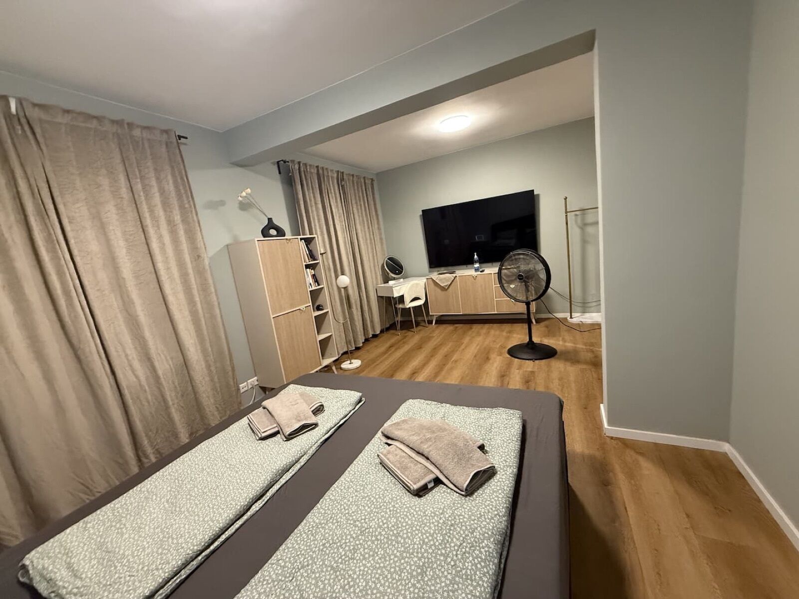 Una habitación de hotel con cama, escritorio, silla, televisor y armario.