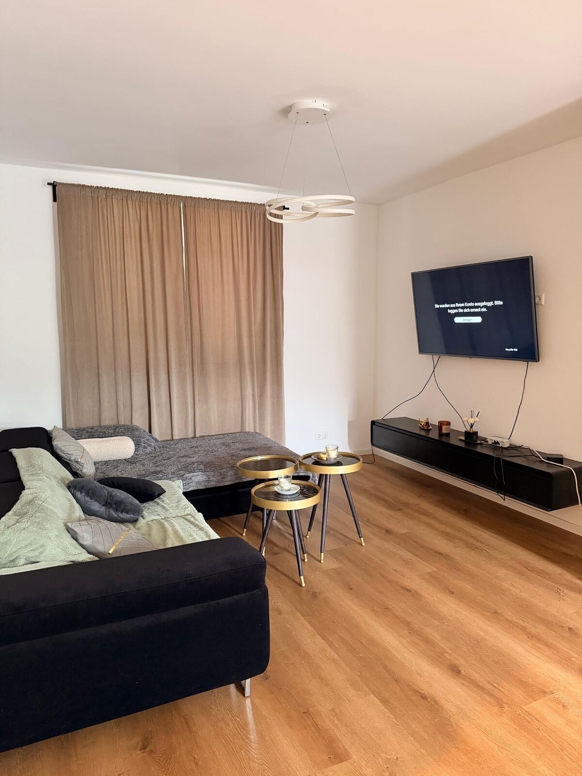 Ein modernes Wohnzimmer mit einer Couch, einem an der Wand montierten Fernseher, einem Couchtisch und einem Beistelltisch.