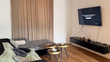 Ein modernes Wohnzimmer mit einer Couch, einem an der Wand montierten Fernseher, einem Couchtisch und einem Beistelltisch.