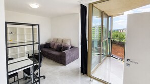 A modern living room with a sofa, a glass table, and a shelving unit. - 2 room Apartment with AC, Vienna Gate 4 (Bratislava)
