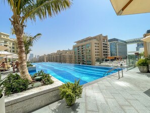 Ein Pool auf dem Dach mit freiem Blick auf die Stadtlandschaft, umgeben von Palmen und modernen Gebäuden.