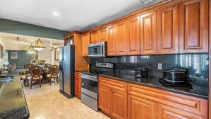 A kitchen with wooden cabinets, stainless steel appliances, and a granite countertop. - Miami Gardens Pool Retreat (Miami Gardens)