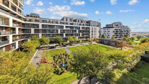 Un edifici residencial de diverses plantes amb balcons, un pati interior i vegetació als voltants.