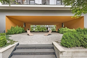 Ein moderner Außenbereich mit zwei Holzliegen, einem Kiesgrund und einer Betontreppe.