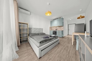A modern bedroom with a bed, wardrobe, and kitchenette.