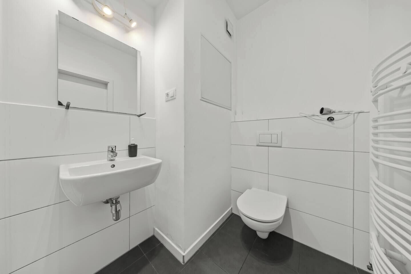 Un bagno moderno con lavandino, water e doccia bianchi.