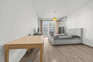 Ein modernes Schlafzimmer mit einem Bett, einem Holztisch und einem Fenster mit Vorhängen.
