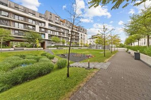 Ein moderner Wohnkomplex mit gepflastertem Weg, Grünflächen und blauem Himmel.
