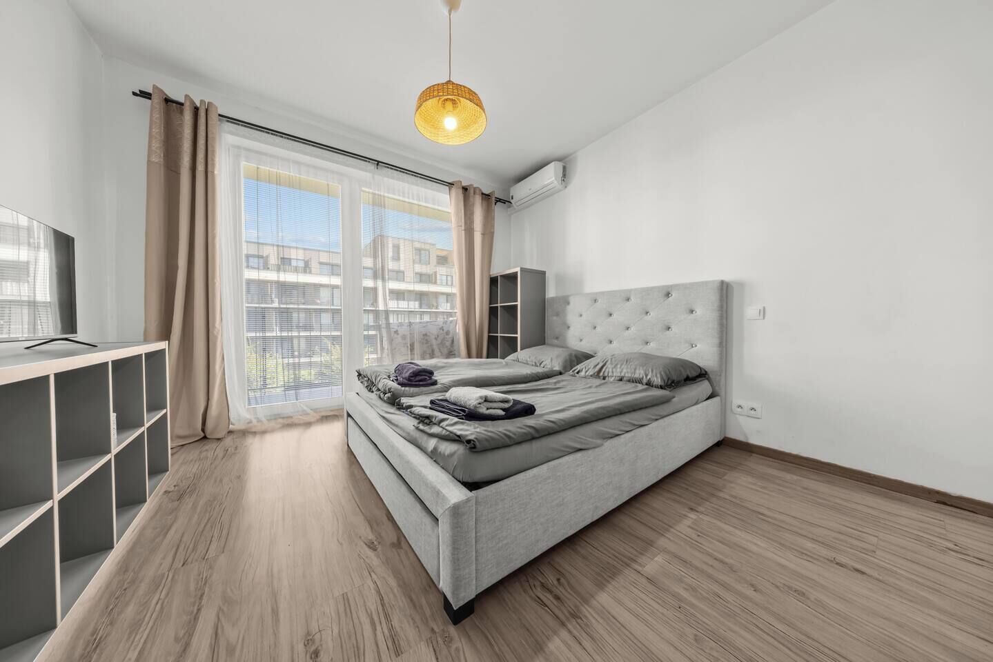 Een moderne slaapkamer met een groot bed, een bureau en een raam met gordijnen.