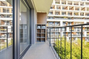 Ein Balkon mit Blick auf ein mehrstöckiges Wohngebäude, einer Glastür und einem Regaleinheit.