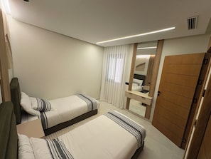 A hotel room with two beds, a wooden wardrobe, a mirror, and a window with curtains. - New luxury apartment near stadium (Tanger)