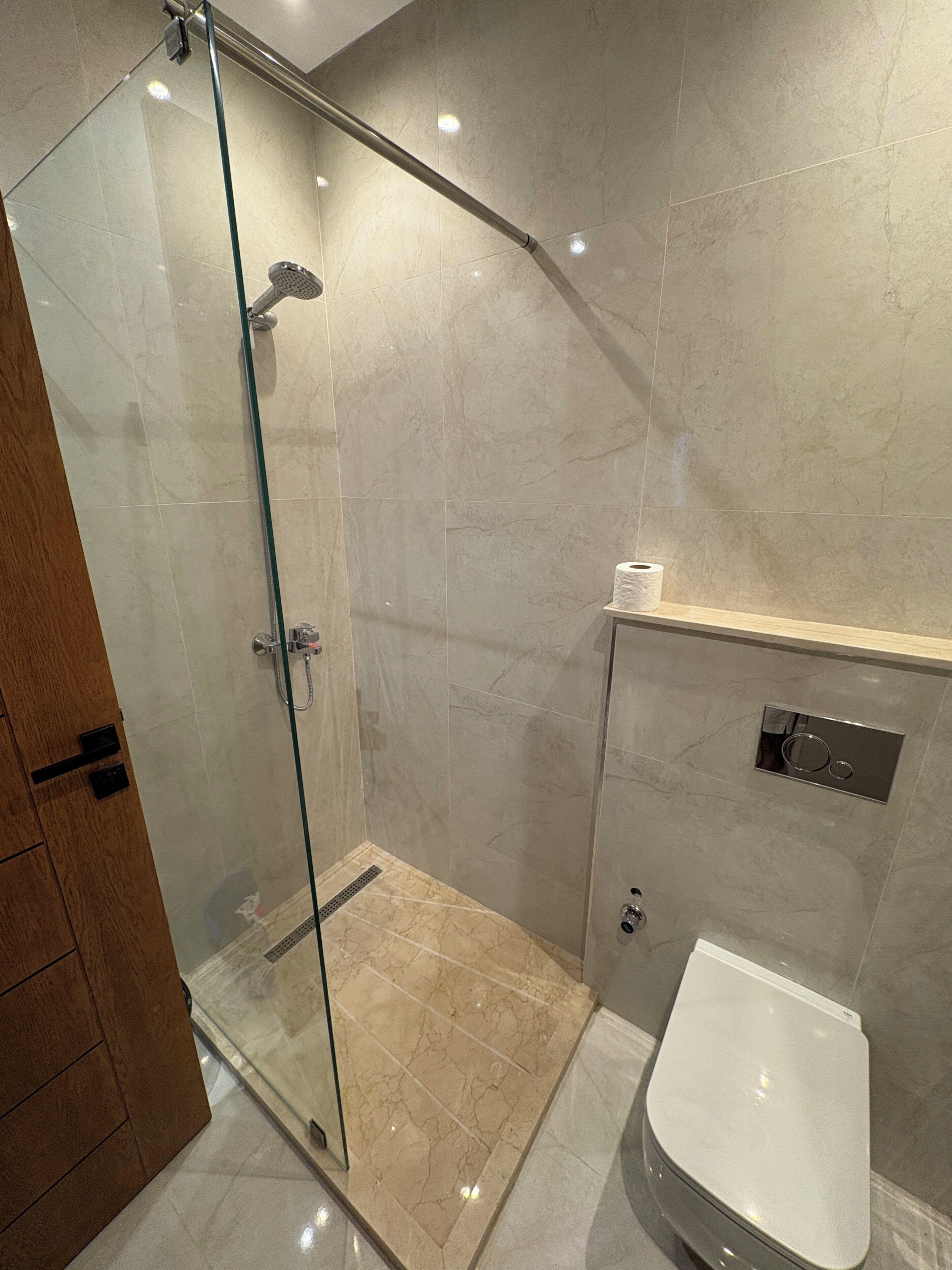 Een moderne badkamer met een douchecabine van glas, een toilet en een wastafel met spiegel.