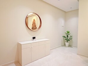 A hallway with a white cabinet, a round mirror, and a potted plant. - New luxury apartment near stadium (Tanger)