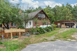A traditional wooden house with a sloped roof, a wooden fence, and a sign that reads 'Jagdhaus An der Nemitzer Heide.' - Apartment 'Jagdhaus An Der Nemitzer Heide' with Wi-Fi (Prezelle)