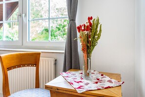 A wooden chair and a table with a clear glass vase containing flowers.
