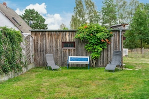 A wooden fence with a bench and two chairs in a backyard. - Apartment 'Jagdhaus An Der Nemitzer Heide' with Wi-Fi (Prezelle)