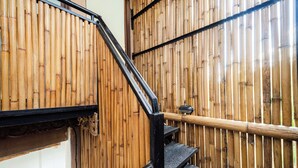 A staircase with a black metal railing and a bamboo wall.