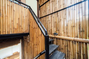 A staircase with a black metal railing and a bamboo wall.