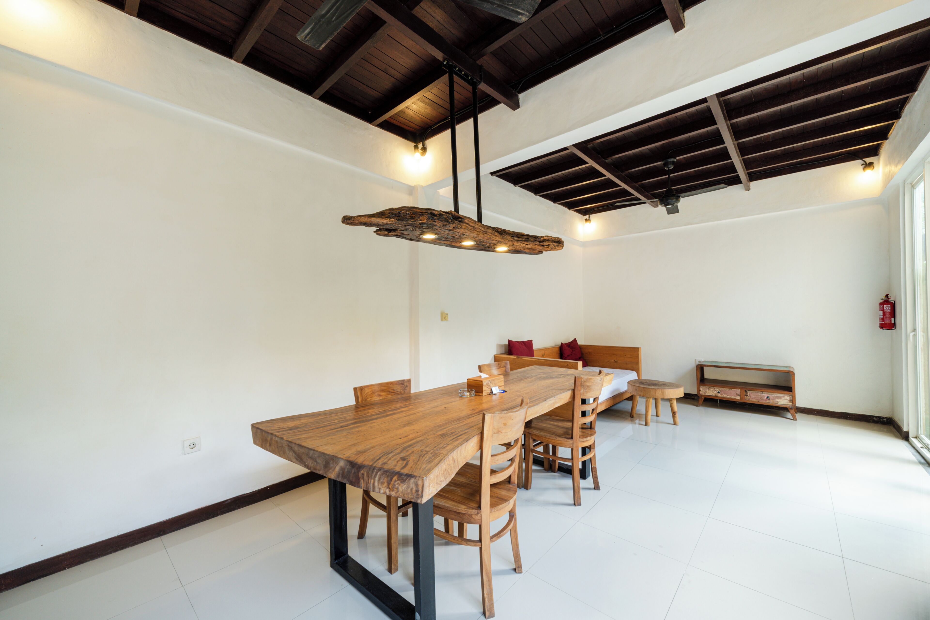 A spacious dining area with a long wooden table, chairs, and a hanging light fixture.