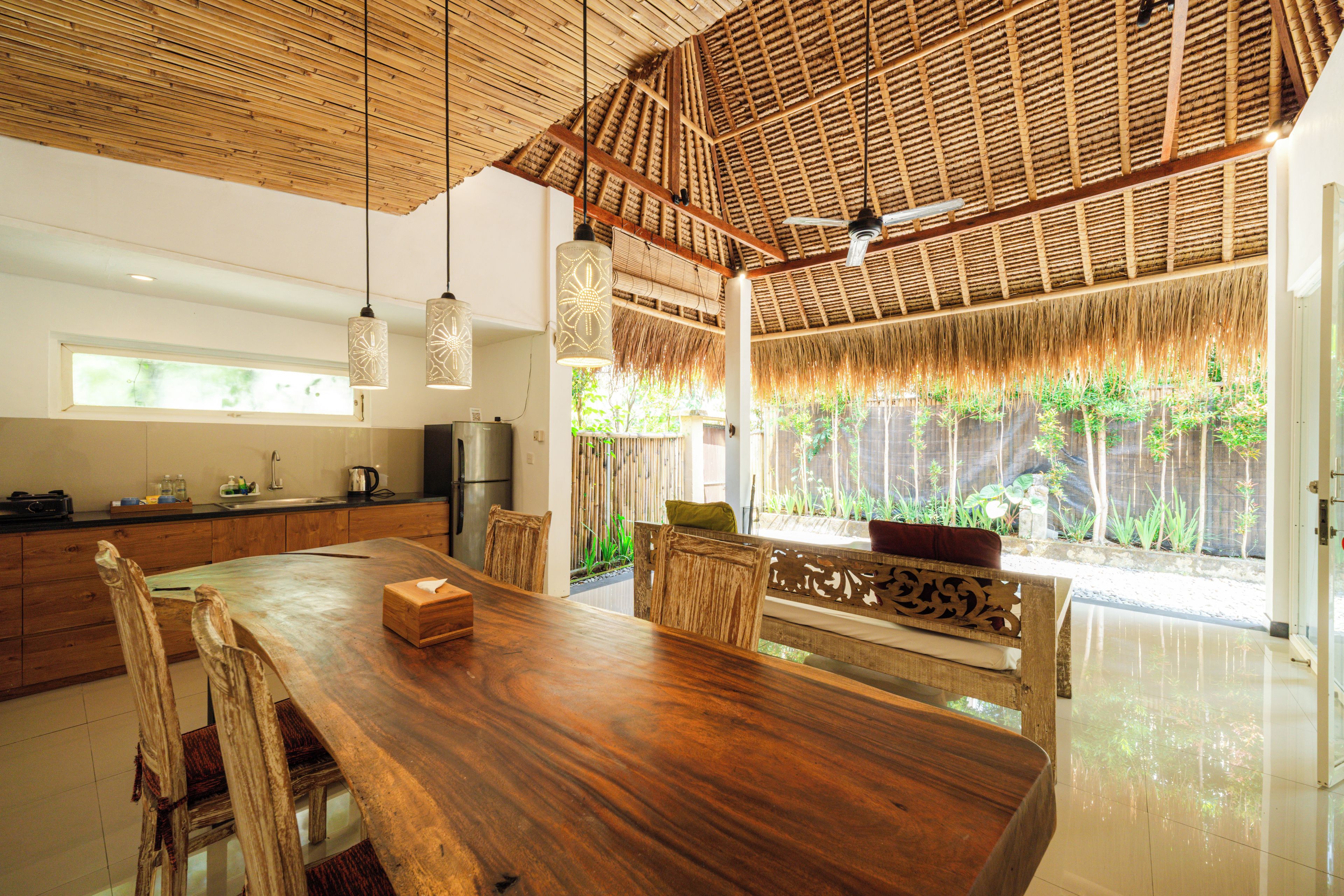A spacious kitchen with a large wooden table, modern appliances, and a view of greenery outside.