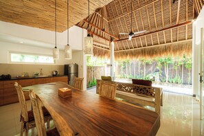 A spacious kitchen with a large wooden table, modern appliances, and a view of greenery outside.