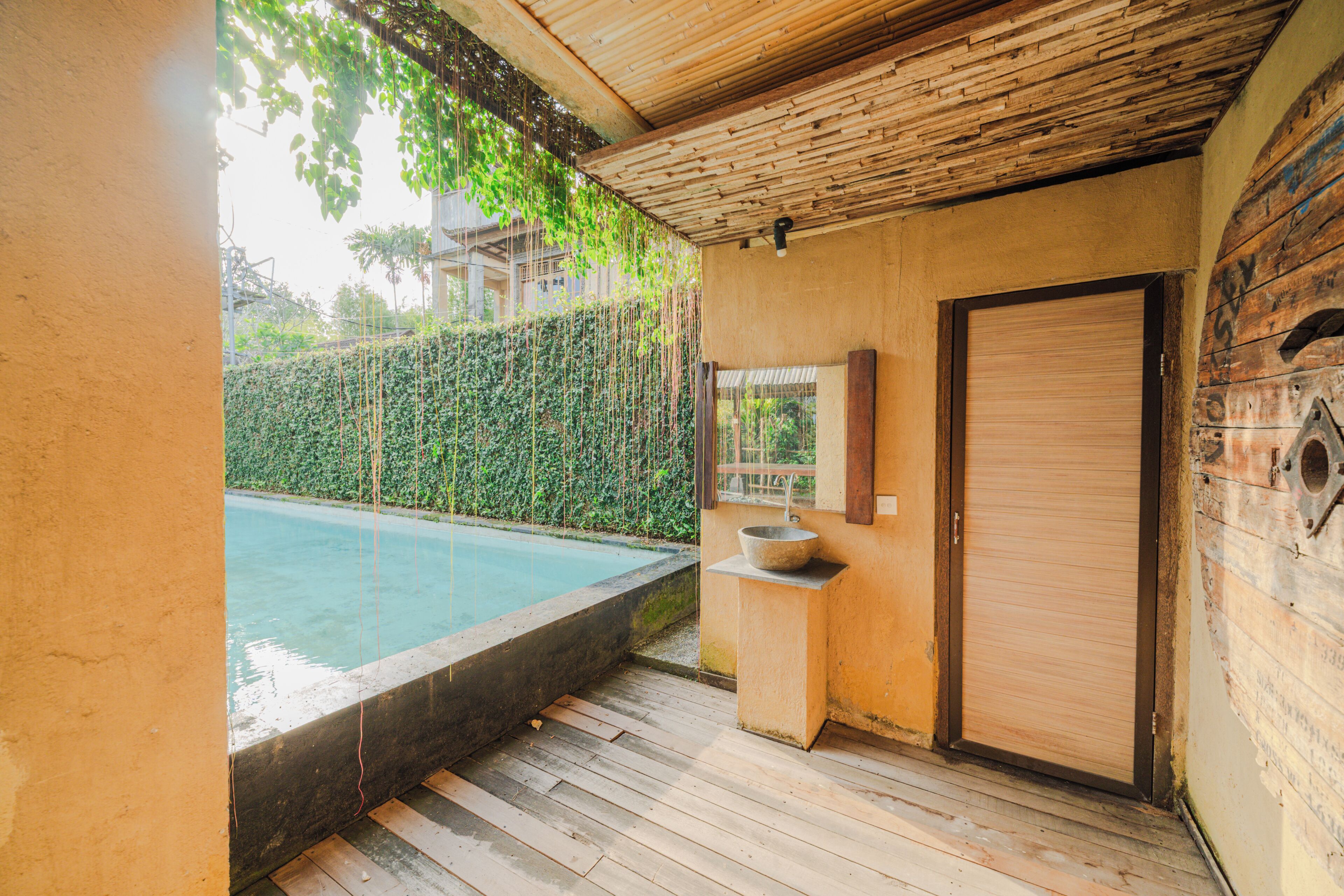 Ein Badezimmer mit Holzboden, einem Waschbecken, einem Spiegel und einer Tür.