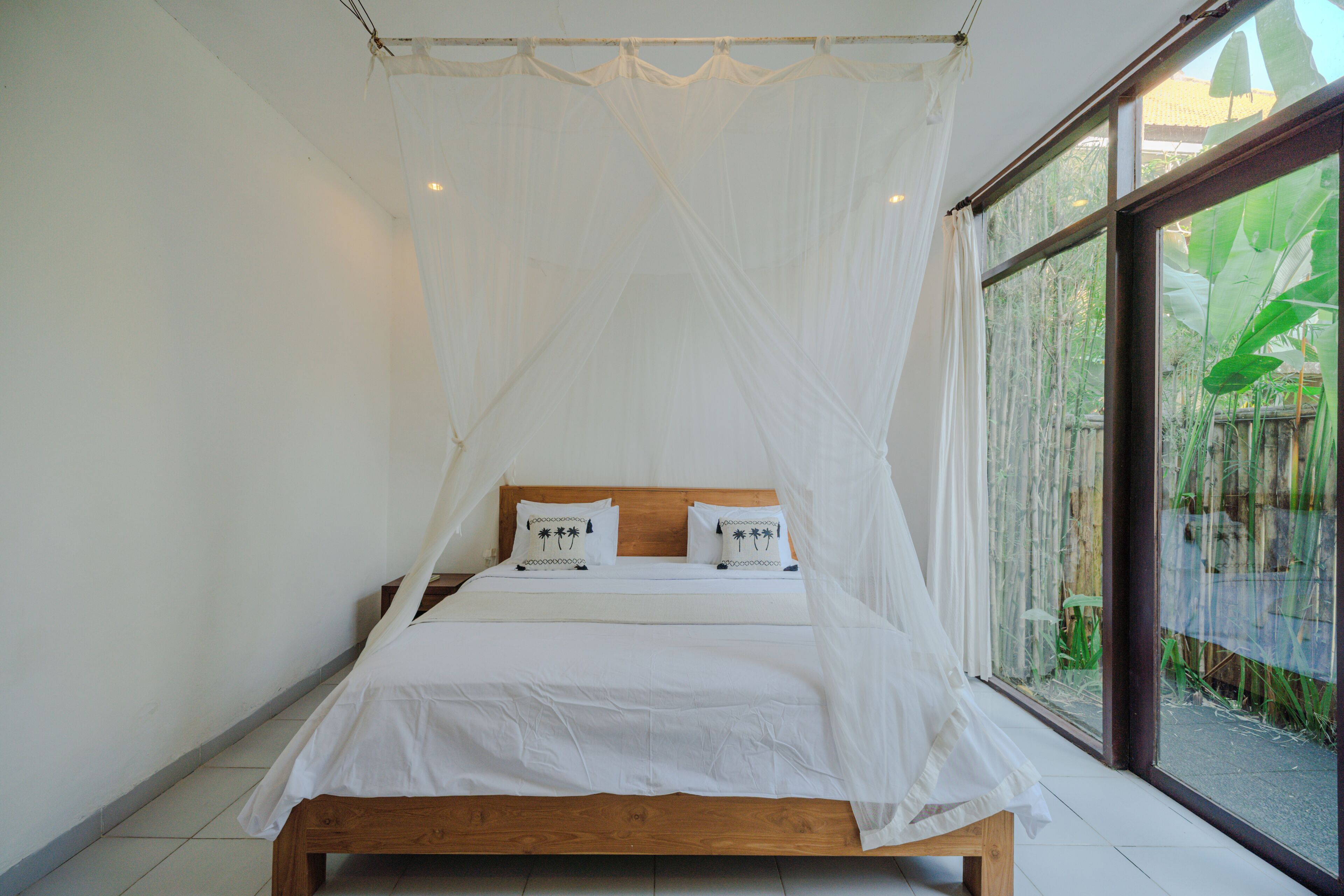 A bed with a wooden frame, white bedding, and a canopy.