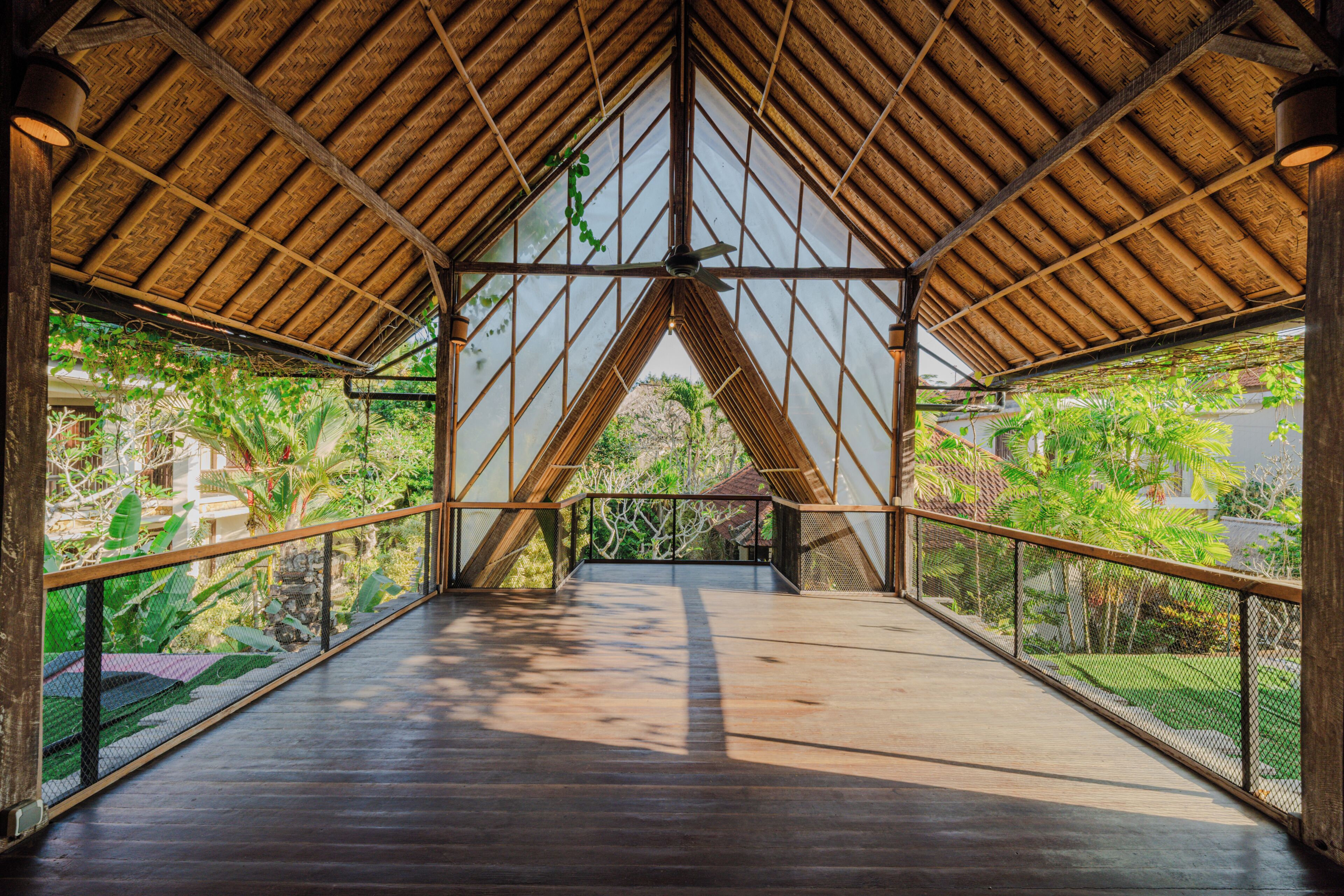 A covered walkway with a wooden floor and metal railings, leading to a glass door.