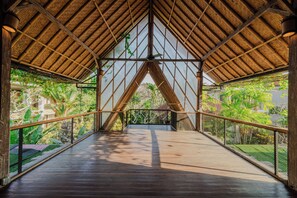Une allée couverte, dotée d’un plancher en bois et de rampes en métal, qui mène à une porte en verre.
